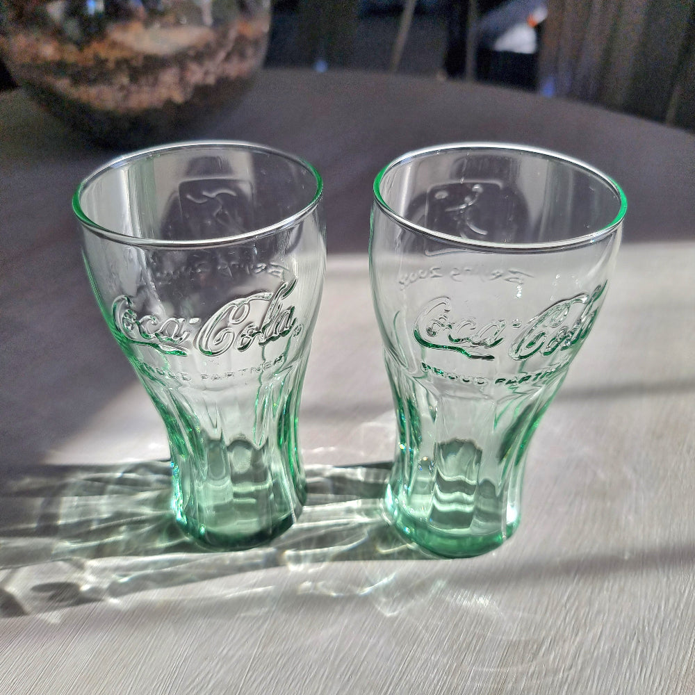 Two green-tinted Coca-Cola Beijing Olympic drinking glasses with embossed Coke logo.