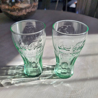 Two green-tinted Coca-Cola Beijing Olympic drinking glasses with embossed Coke logo.