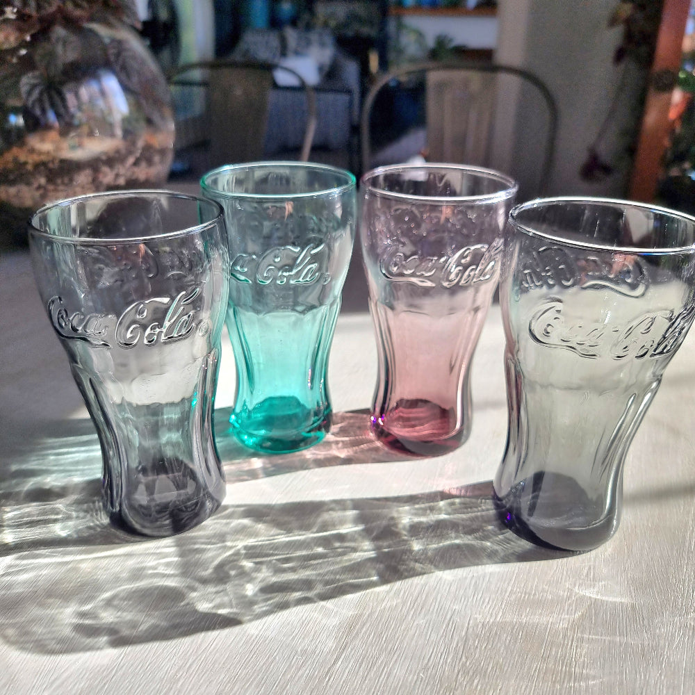 Set of four coloured Coca-Cola drinking glasses with embossed Coke logo in grey, aqua, pink and charcoal glass.