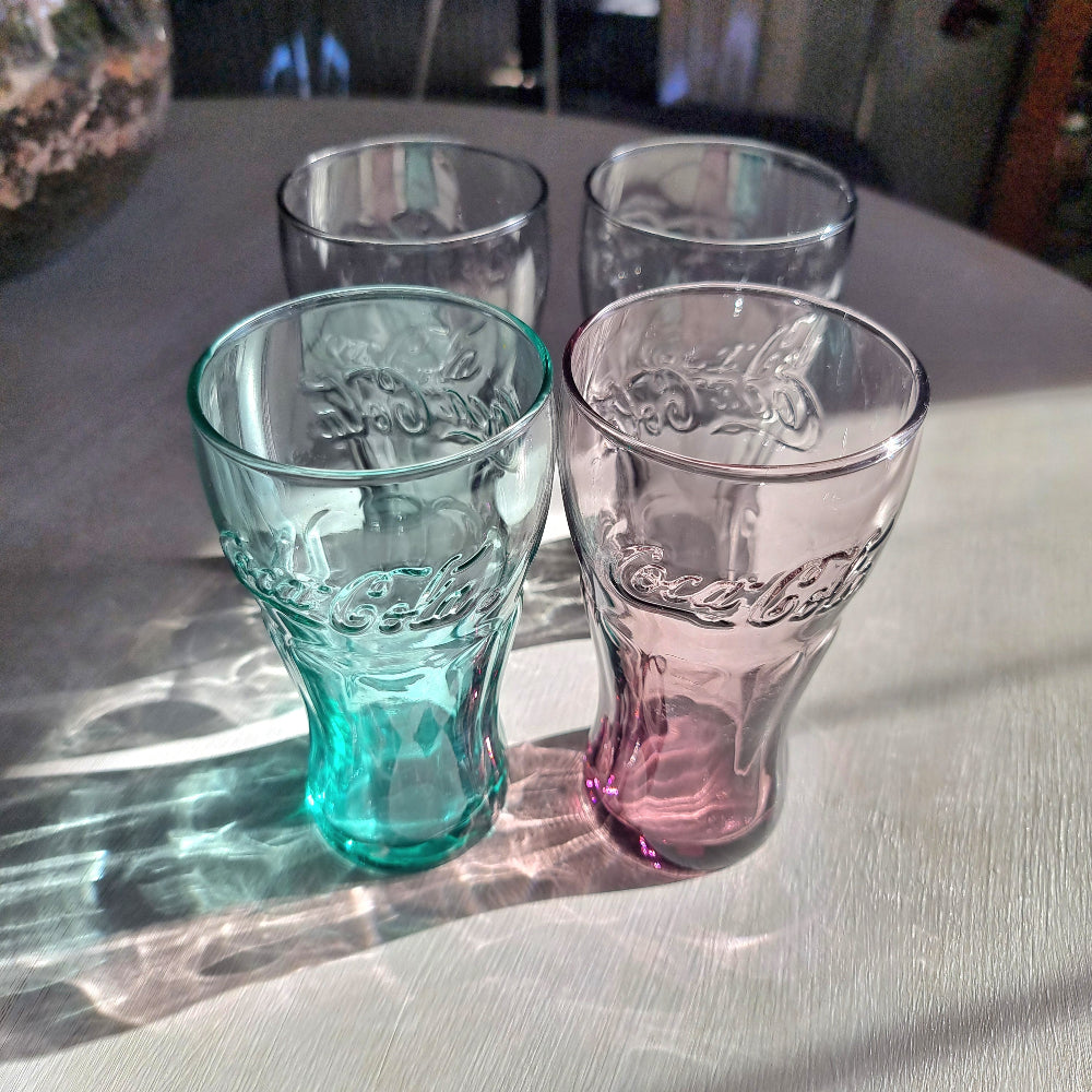 Set of four coloured Coca-Cola drinking glasses with embossed Coke logo in grey, aqua, pink and charcoal glass.
