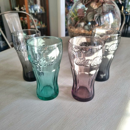 Set of four coloured Coca-Cola drinking glasses with embossed Coke logo in grey, aqua, pink and charcoal glass.