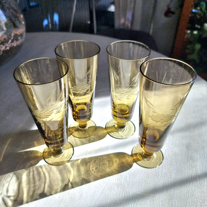 Set of four amber champagne flutes with etched floral pattern and short stems