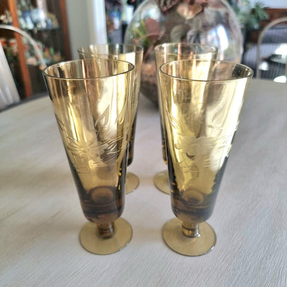 Set of four amber champagne flutes with etched floral pattern and short stems