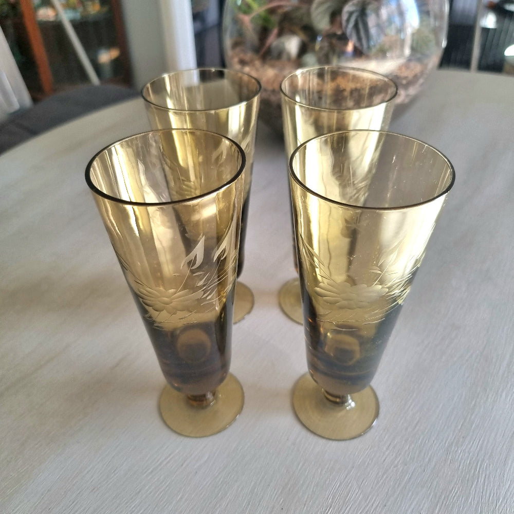 Set of four amber champagne flutes with etched floral pattern and short stems