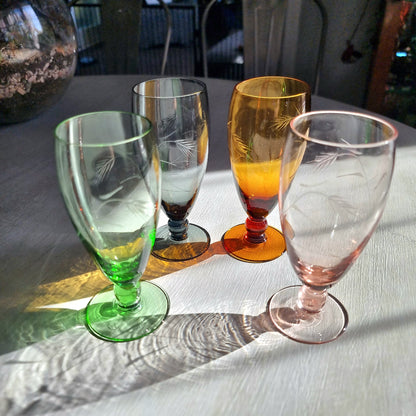 Set of four coloured champagne flutes in green, amber, blue and pink with etched pattern