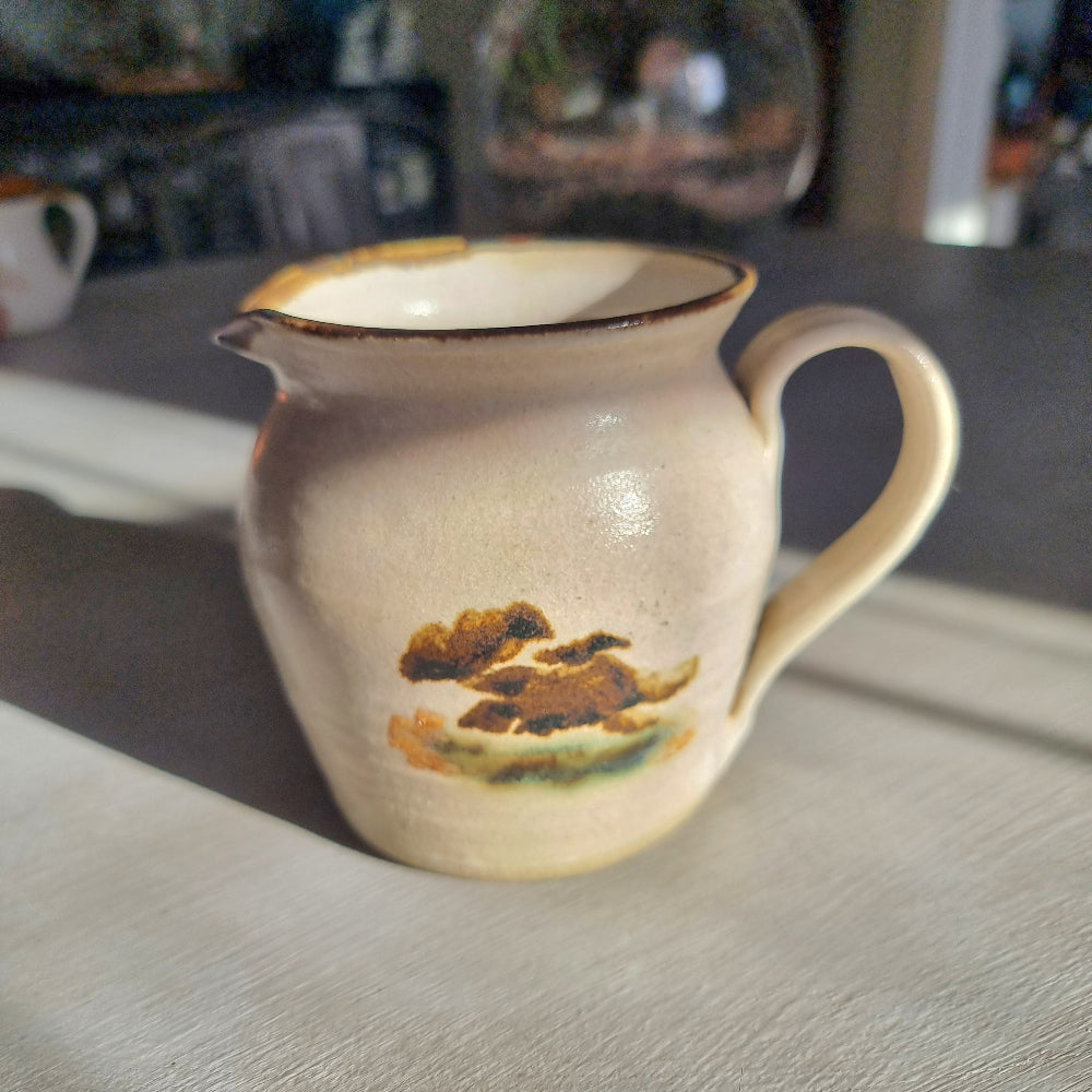 Vintage studio pottery cream jug with speckled sandy glaze and abstract brushwork