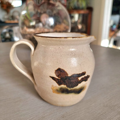 Vintage studio pottery cream jug with speckled sandy glaze and abstract brushwork