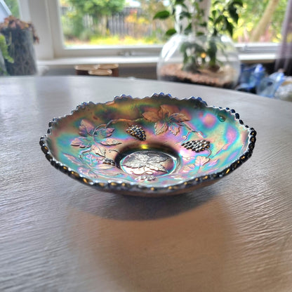 Vintage Fenton carnival glass berry bowl with iridescent rainbow finish and raised grapevine pattern.