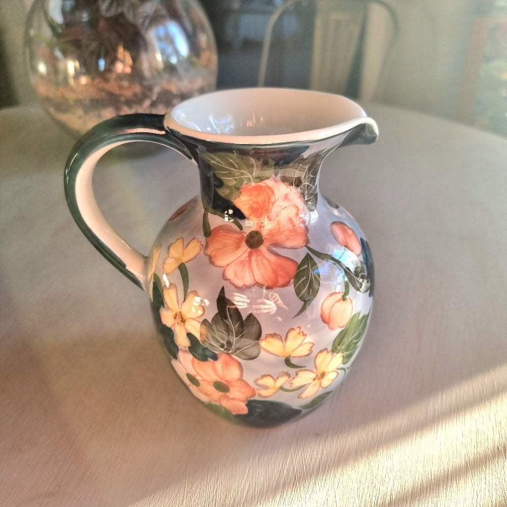 Large vintage hand-painted ceramic jug with pink and yellow floral design on periwinkle white glaze, forest green handle and neck trim