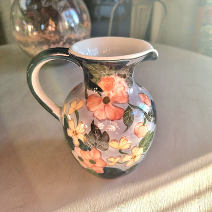 Large vintage hand-painted ceramic jug with pink and yellow floral design on periwinkle white glaze, forest green handle and neck trim