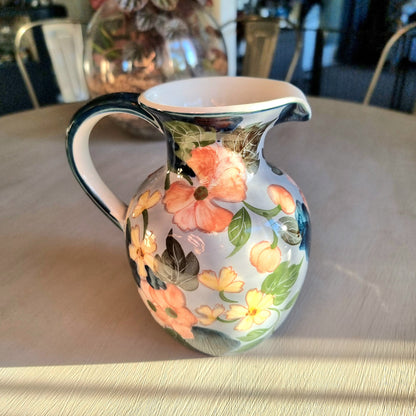 Large vintage hand-painted ceramic jug with pink and yellow floral design on periwinkle white glaze, forest green handle and neck trim