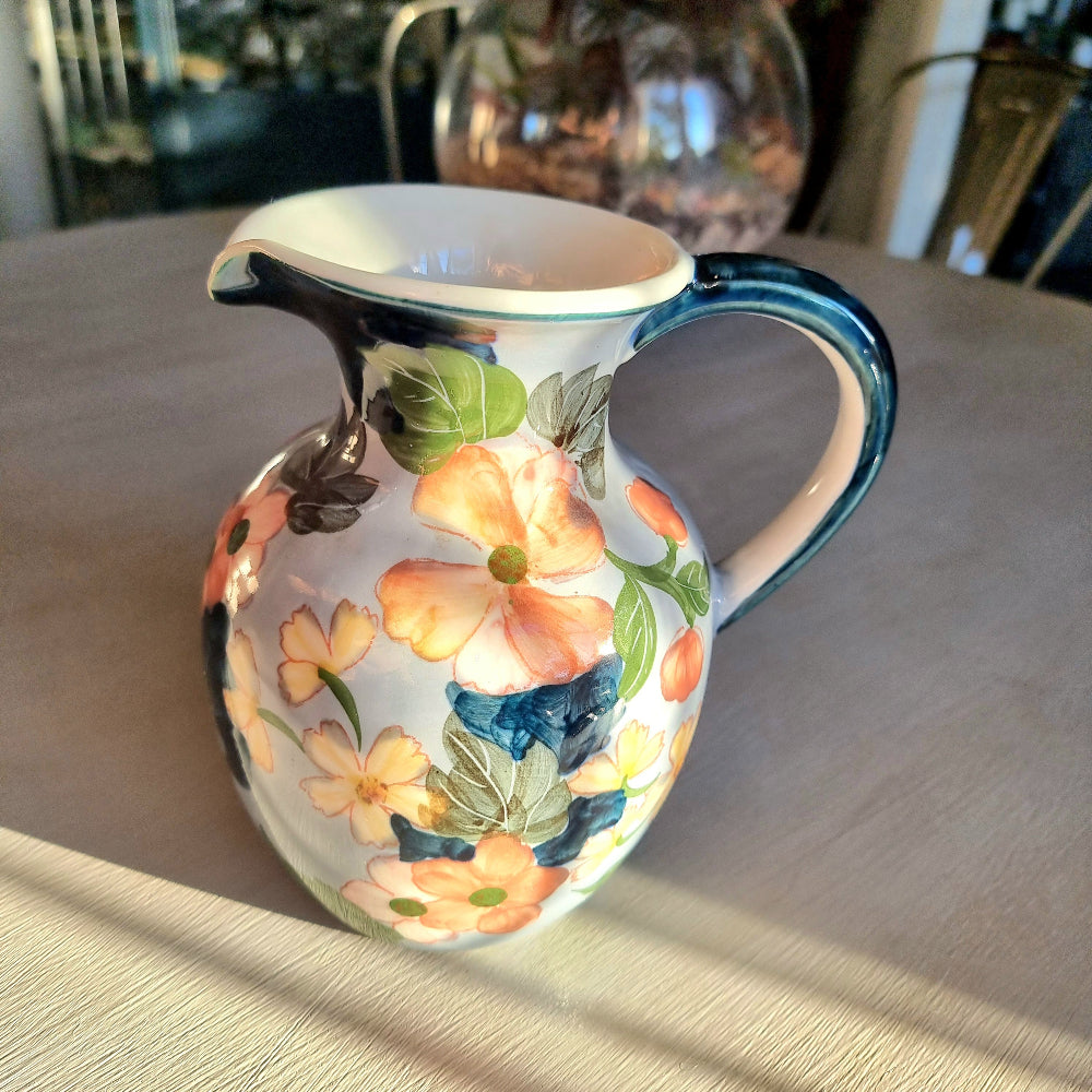 Large vintage hand-painted ceramic jug with pink and yellow floral design on periwinkle white glaze, forest green handle and neck trim
