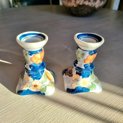 Pair of vintage hand-painted ceramic candlestick holders with orange peach and pink floral design on white glaze with cobalt blue brushstrokes and trim, flared square base