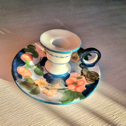 Vintage hand-painted ceramic chamberstick candle holder with coral and yellow floral design on white and periwinkle glaze, turquoise teal accent trim and loop handle