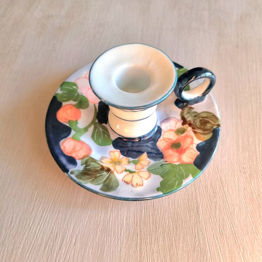 Vintage hand-painted ceramic chamberstick candle holder with coral and yellow floral design on white and periwinkle glaze, turquoise teal accent trim and loop handle
