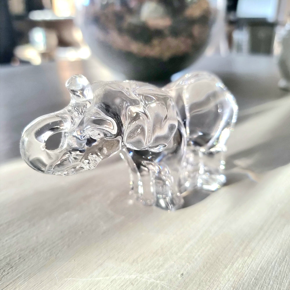 Villeroy and Boch clear crystal glass elephant figurine with raised trunk in walking pose, refracting light on a pale wooden surface