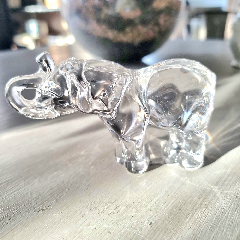 Villeroy and Boch clear crystal glass elephant figurine with raised trunk in walking pose, refracting light on a pale wooden surface