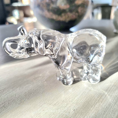 Villeroy and Boch clear crystal glass elephant figurine with raised trunk in walking pose, refracting light on a pale wooden surface