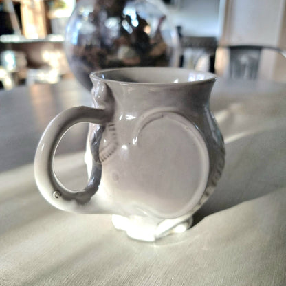 Jonathan Adler Utopia white stoneware elephant mug with trunk spout and tail handle, glossy glaze, viewed from the side on a pale surface