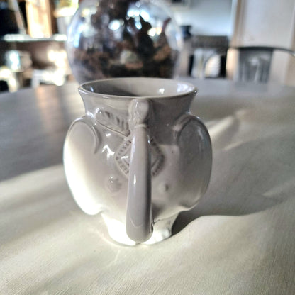 Jonathan Adler Utopia white stoneware elephant mug with trunk spout and tail handle, glossy glaze, viewed from the side on a pale surface