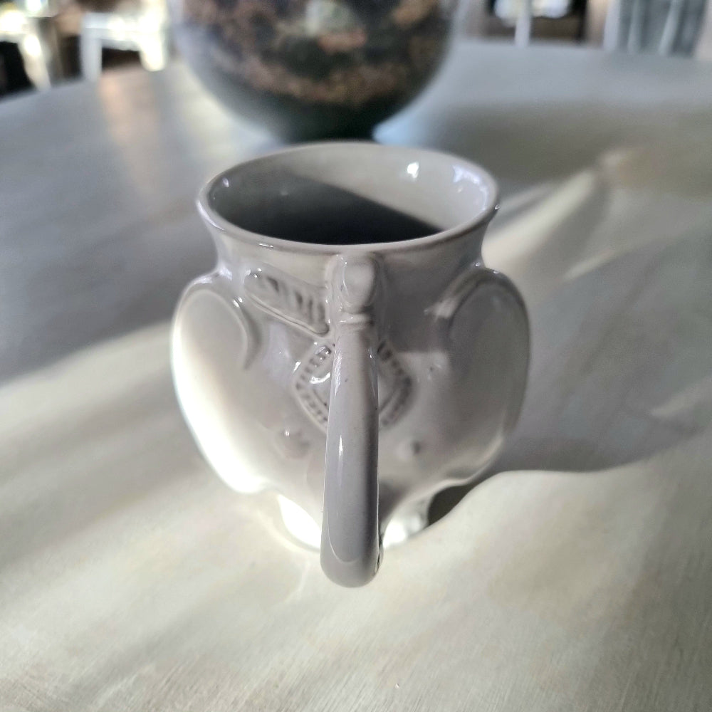 Jonathan Adler Utopia white stoneware elephant mug with trunk spout and tail handle, glossy glaze, viewed from the side on a pale surface