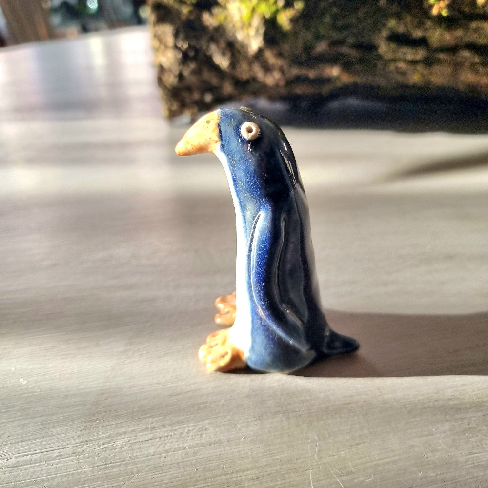 Vintage hand-painted ceramic penguin figurine with navy blue glaze, white front and orange feet