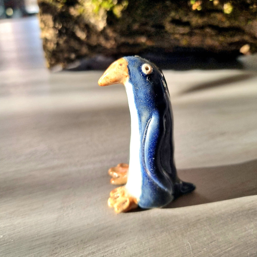 Vintage hand-painted ceramic penguin figurine with navy blue glaze, white front and orange feet