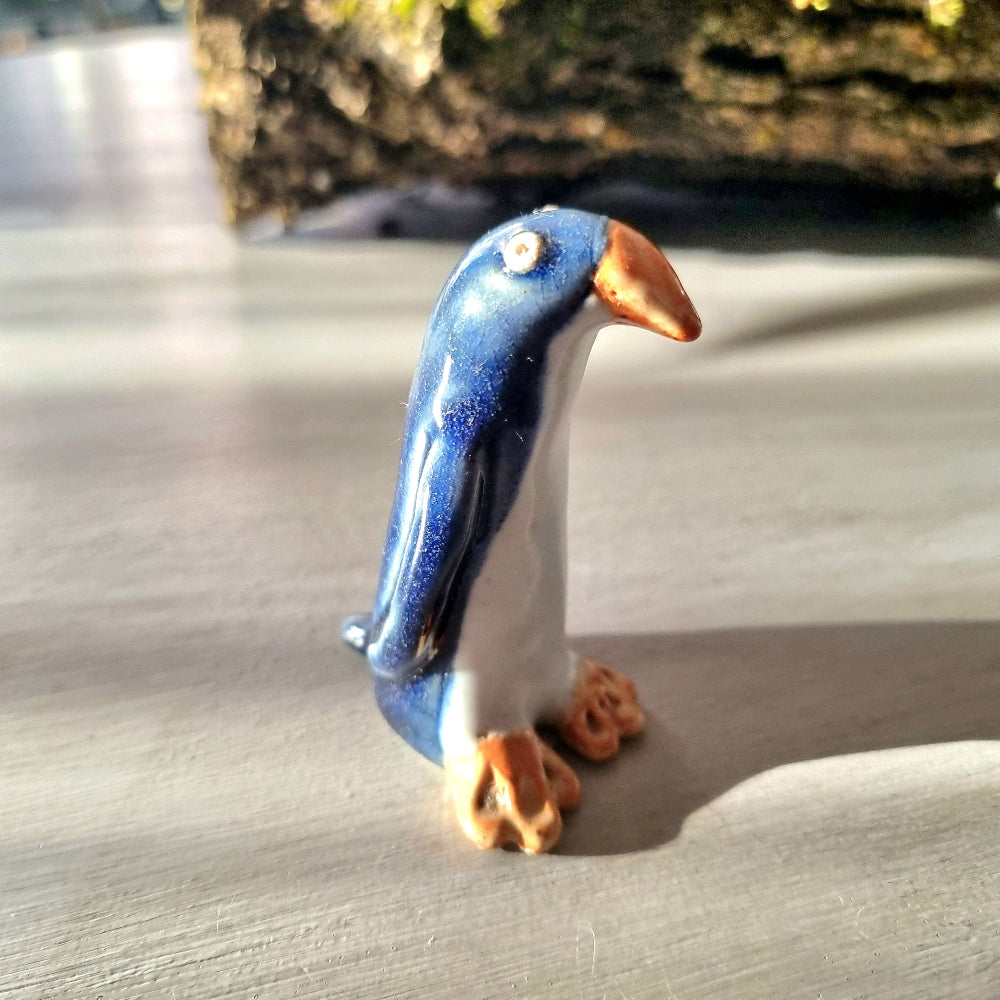 Vintage hand-painted ceramic penguin figurine with navy blue glaze, white front and orange feet