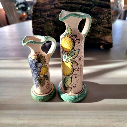 Pair of hand-painted Deruta-style ceramic jug vases with grape and lemon motifs, on wooden bases