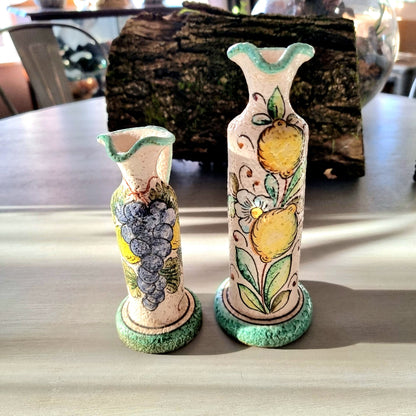 Pair of hand-painted Deruta-style ceramic jug vases with grape and lemon motifs, on wooden bases