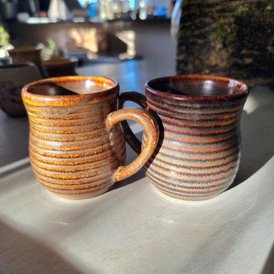 Pair of vintage ribbed mugs with amber and brown drip glaze, one with a small glaze nick on the rim