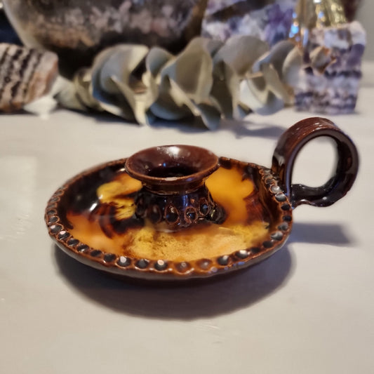 Vintage ceramic chamberstick candle holder with mottled brown and amber glaze, beaded rim, and ring handle
