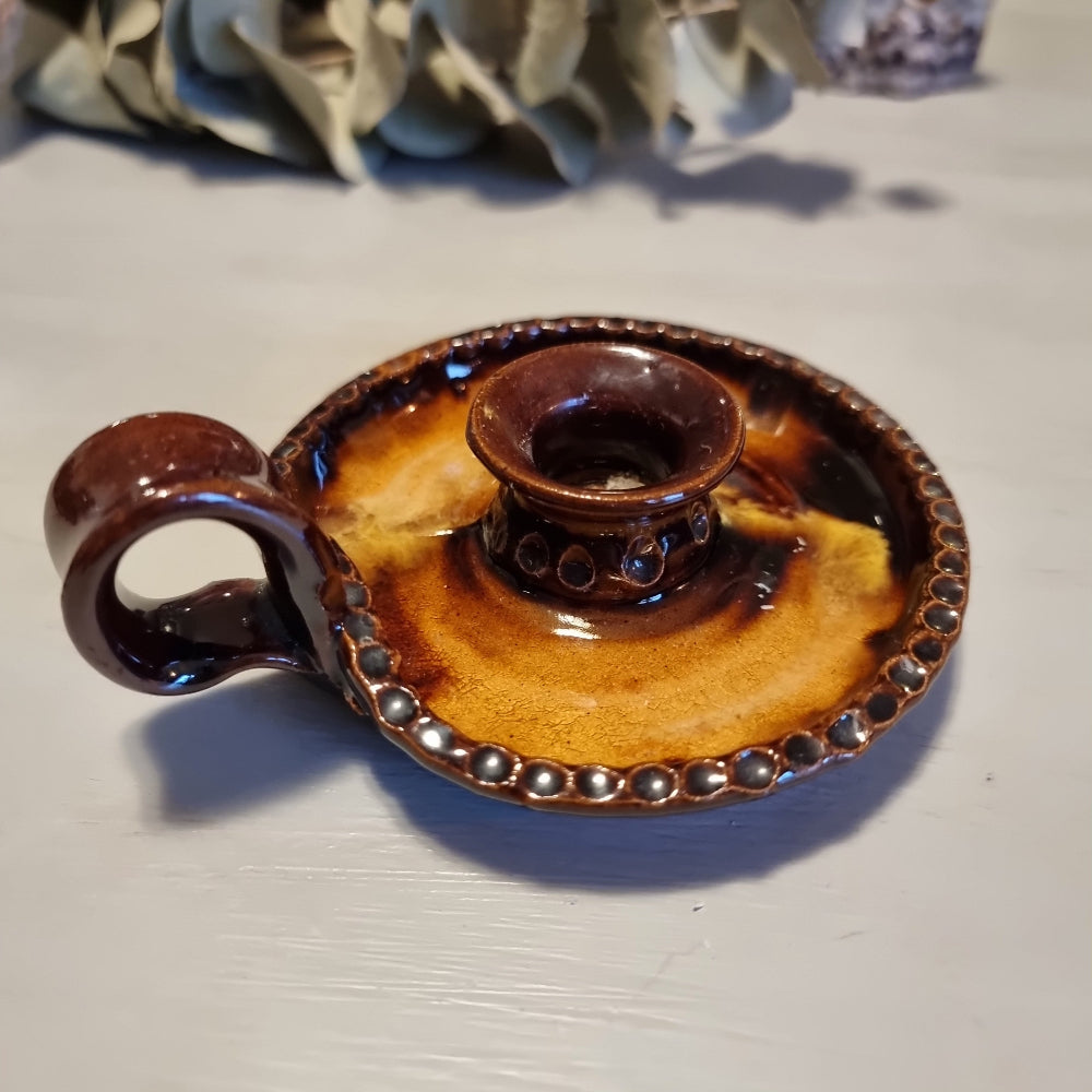 Vintage ceramic chamberstick candle holder with mottled brown and amber glaze, beaded rim, and ring handle