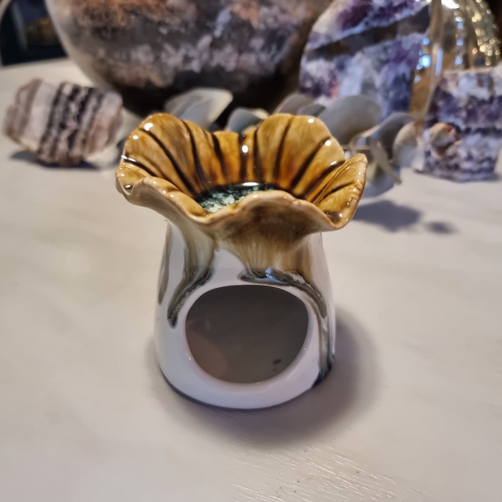 Ceramic oil burner with scalloped flower-shaped top in honey and amber striped glaze, on a white cylindrical base with heat vent