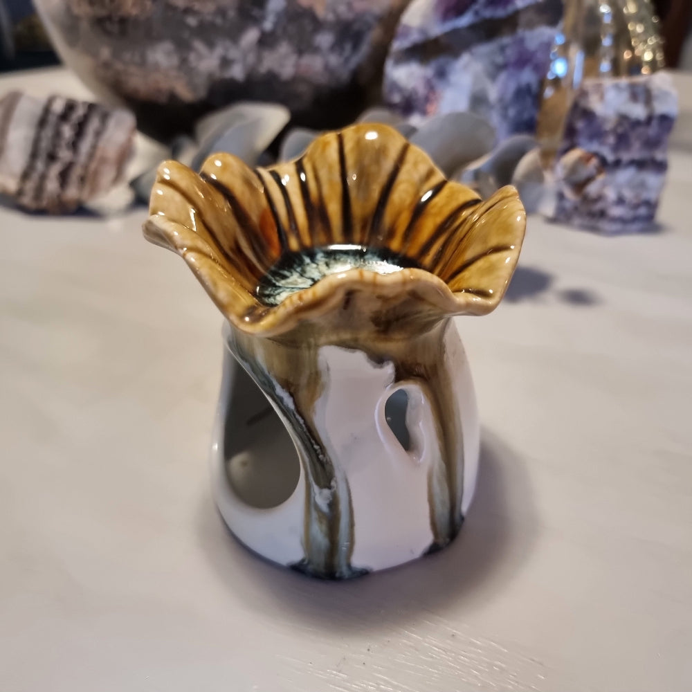 Ceramic oil burner with scalloped flower-shaped top in honey and amber striped glaze, on a white cylindrical base with heat vent