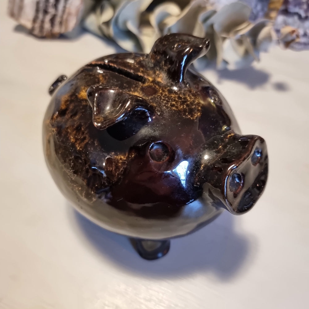 Vintage ceramic piggy money box in mottled brown glaze with speckled highlights, standing on four legs with a coin slot