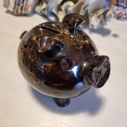 Vintage ceramic piggy money box in mottled brown glaze with speckled highlights, standing on four legs with a coin slot
