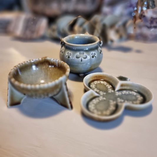 Trio of vintage Wade shamrock dishes in grey-blue glaze with honey brown highlights, including a footed dish, a pierced pot with wire handle, and a clover-shaped dish