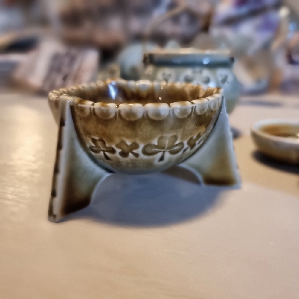 Trio of vintage Wade shamrock dishes in grey-blue glaze with honey brown highlights, including a footed dish, a pierced pot with wire handle, and a clover-shaped dish
