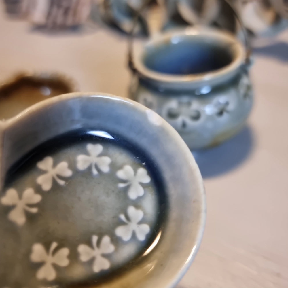 Trio of vintage Wade shamrock dishes in grey-blue glaze with honey brown highlights, including a footed dish, a pierced pot with wire handle, and a clover-shaped dish