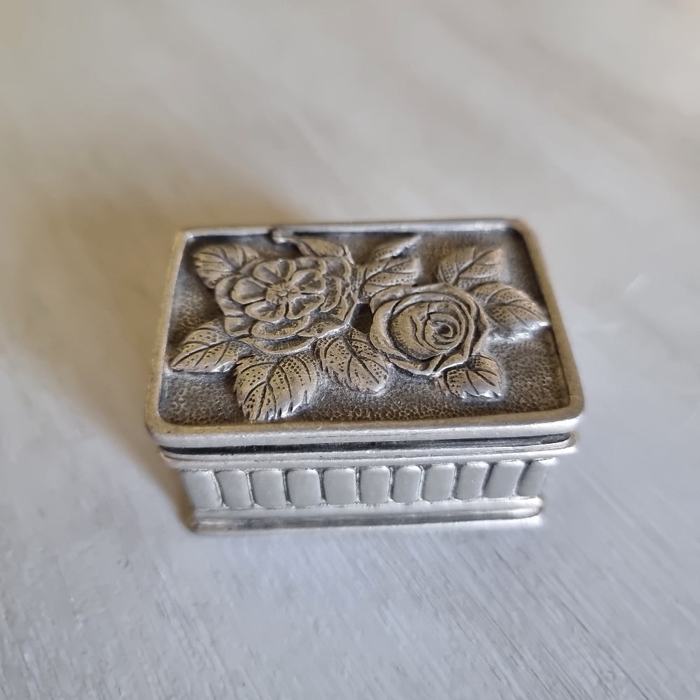 Small metal trinket box with a raised rose lid design