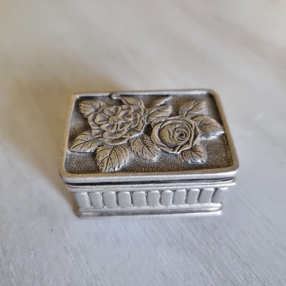 Small metal trinket box with a raised rose lid design