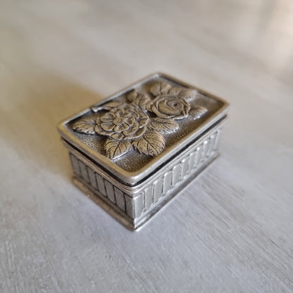 Small metal trinket box with a raised rose lid design