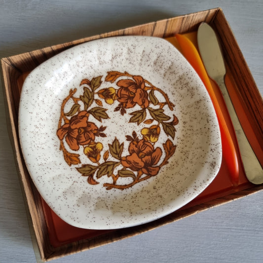 Vintage Palissy speckled plate with orange and brown flowers in a wood-look box with an orange handled knife