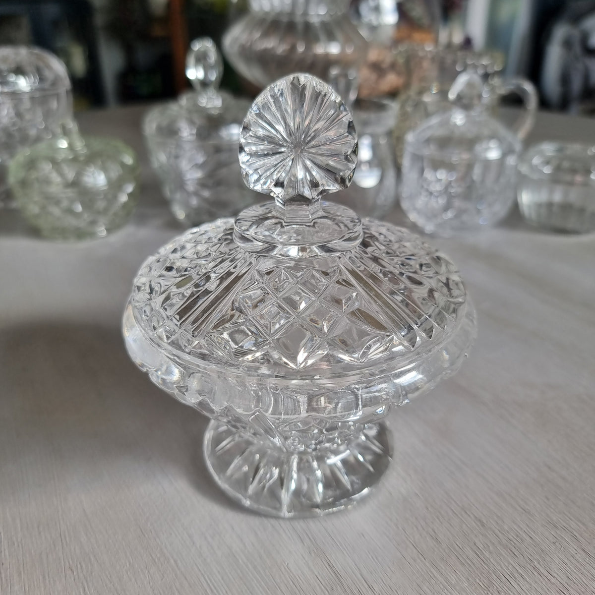 Clear cut glass lidded compote with diamond cut dome lid, fan shaped finial and pedestal foot