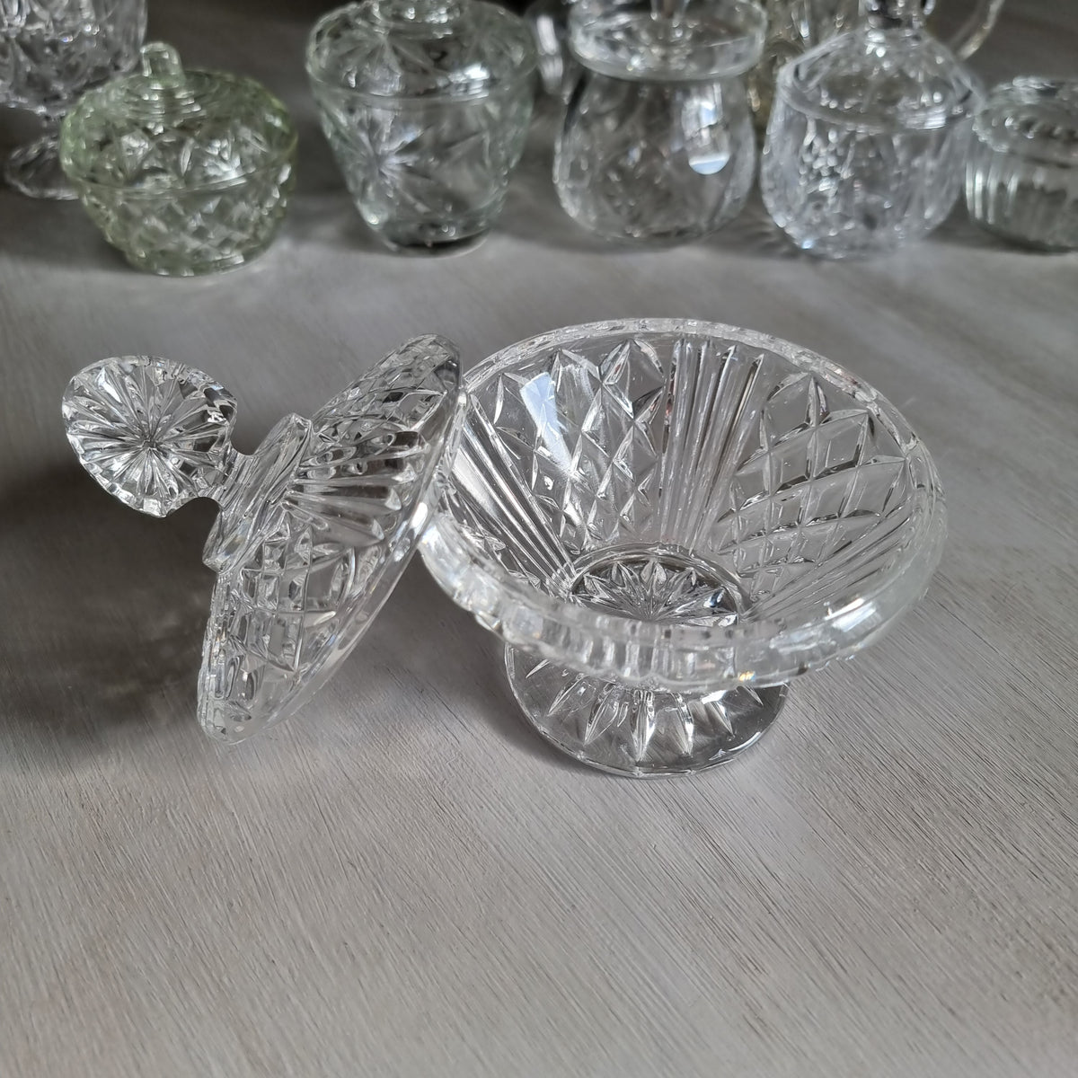 Clear cut glass lidded compote with diamond cut dome lid, fan shaped finial and pedestal foot