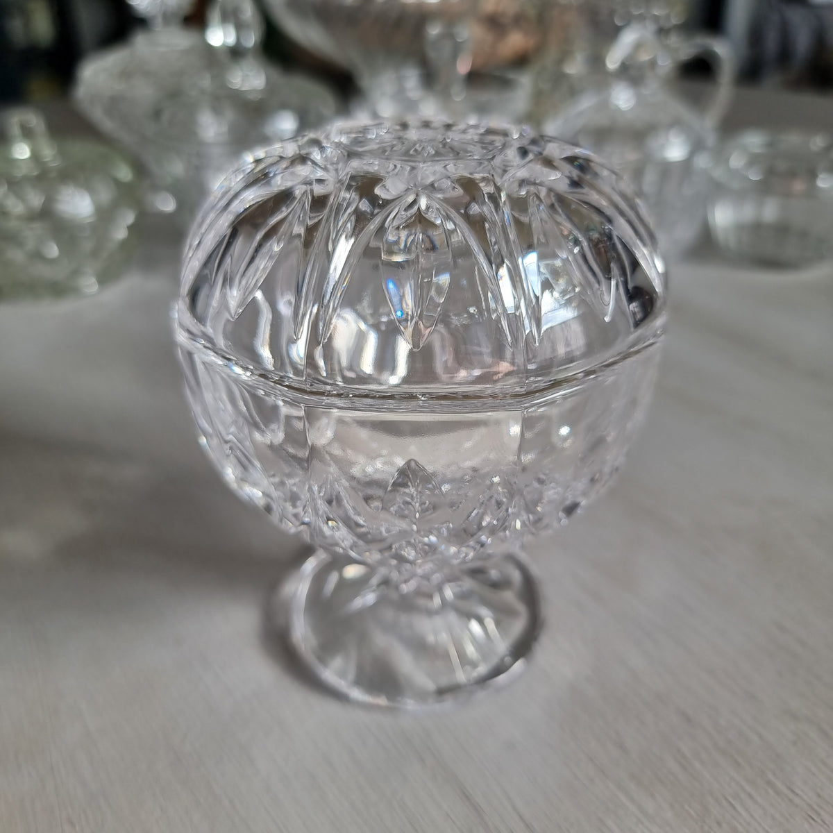 Clear cut crystal footed compote with a rounded dome lid with arched cuts and a star to the top