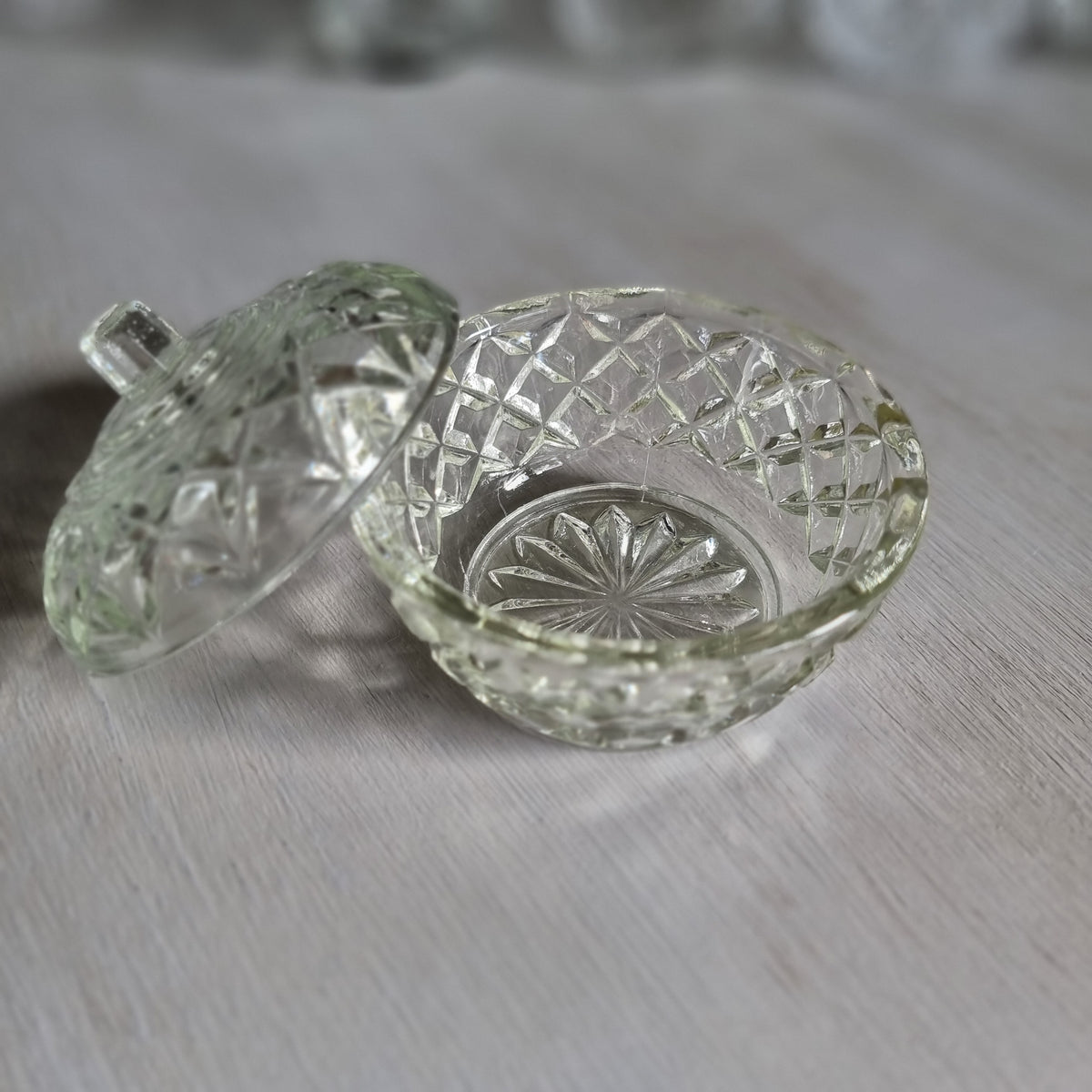 Small round clear glass lidded trinket bowl with diamond and star pattern and a knob lid