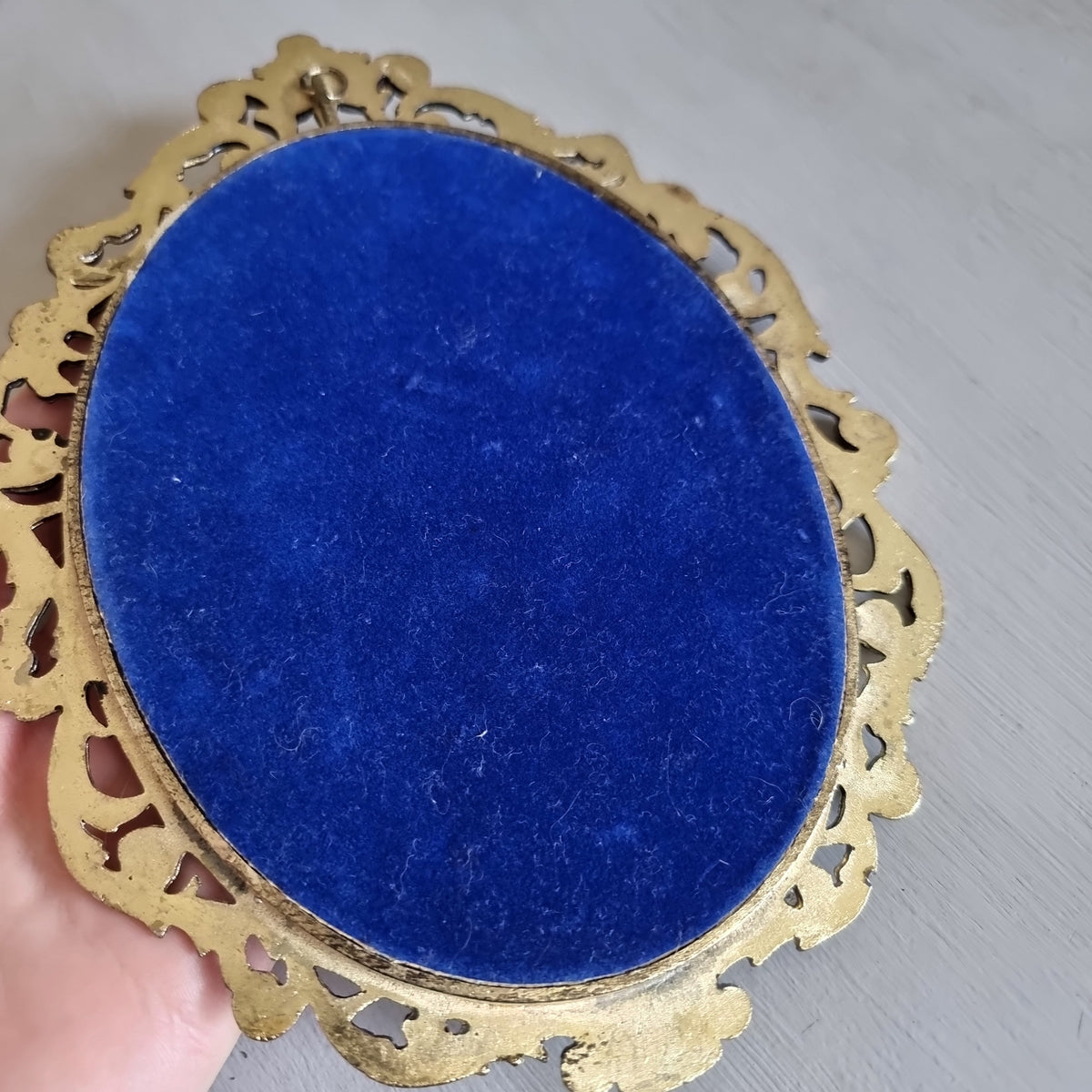 Ornate gold-tone brass oval frame with a silk print of a boy in a red jacket holding a small white dog