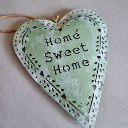 Sage green metal heart with Home Sweet Home cut out in the centre and a punched heart and leaf border, hanging from twine